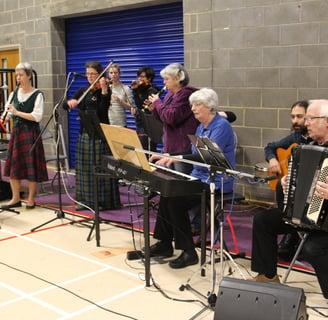 Musicians practicing next to a stage in a gymnasium 