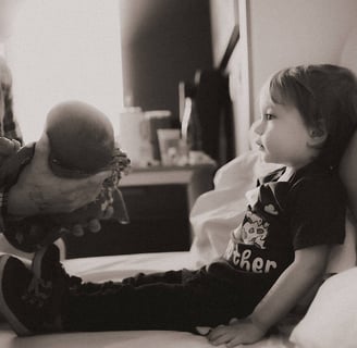 Big Brother getting ready to hold baby brother for the first time