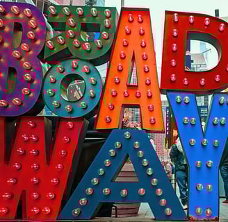 brightly colored "BROADWAY" sign with illuminated bulbs stands in Times Square, New York City