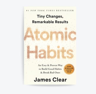 a cup of coffee and the book Atomic Habits on a table
