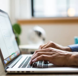 Hands typing a report on a laptop