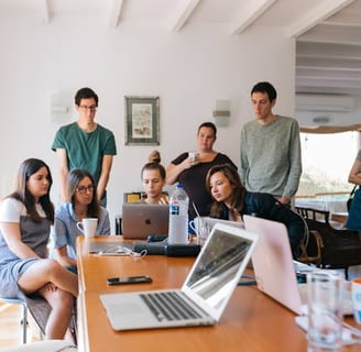 A team gathered around a laptop on a table, attending a virtual meeting.