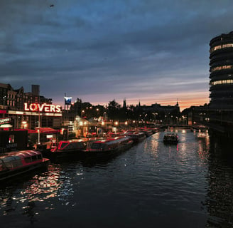 a river with boats and buildings in the background