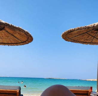 a person's feet in the sand near a beach