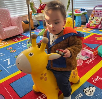 Photo of child playing on a yellow bouncy toy.