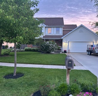 a beautiful, pressure washed home with power washing equipment in driveway during a sunrise 