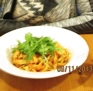 femme assise au restaurant devant une assiette de pâtes 