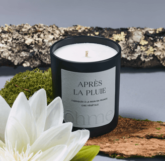 a fall scented candle with a white flower on a table