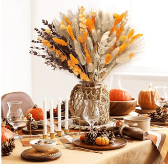 a table with a vase filled with flowers, pumpkin and candles
