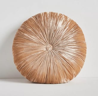 a beige round velvet pillow