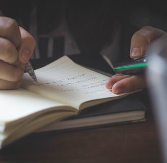 a person writing on a notebook with a pen and a pen