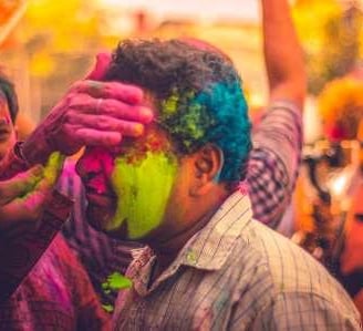 Man celebrating Holi in India with vibrant colors during a trip to India