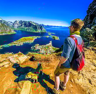 Hiker and dog overlooking Reine from Reinebringen summit near Maritime Munchies fish and chips
