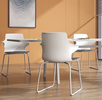 Stackable white meeting chairs with arms around a round table in bright office space
