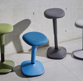 Upholstered motion stools in blue, grey, green with rounded seats and weighted bases