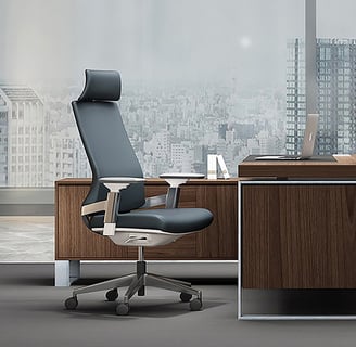Executive high-back office chair in dark grey with headrest, at a modern wooden desk