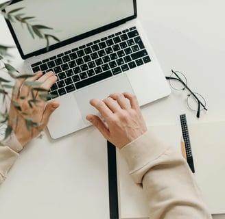 a person's hands typing on a laptop computer
