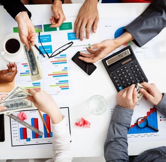 a group of people sitting around a table with money