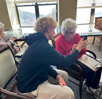 boy helping elderly woman learn how to add a new app on with her iphone
