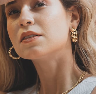 Foto de metade do rosto de uma mulher mostrando boca e brincos de argola em dourado.
