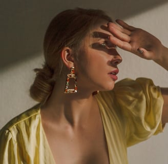 Foto de mulher usando brincos pendentes com pedras coloridas.