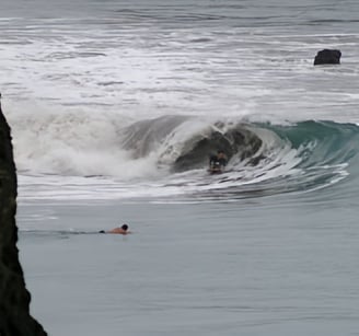 A bodyboarder riding a wave and another surfer watching from the water