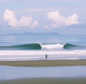 Surfer running on the beach with a perfect wave and an island on the back on a sunny day