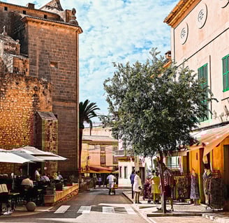 Town in Mallorca with people walking and sitting near an old building