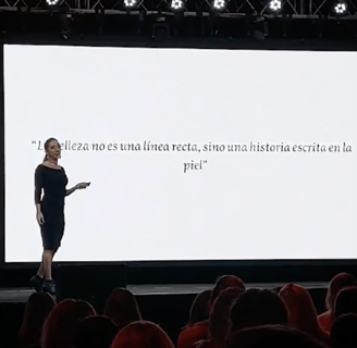 a woman standing on a stage with a white screen Dra Flavia Ward