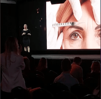 a woman is standing in front of a large screen Dra Flavia Ward