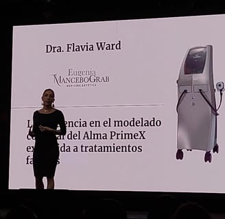 a woman standing on a stage with a large screen Dra Flavia Ward