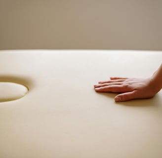 Relaxing atmosphere, one hand is placed on the cream-colored massage table