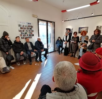 a group of people sitting in a circle with a man in a red hat