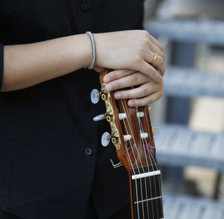 a woman in a suit and tie holds a guitar