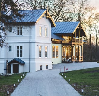 A stately white house surrounded by trees and lush grass