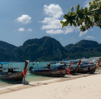 Long-tail boats, turquoise waters, and limestone cliffs at Tonsai Bay in Phi Phi Islands