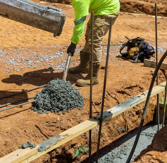 a man in a yellow jacket is pouring concrete into a concrete slab