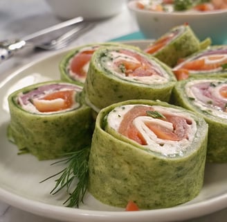 a plate of food that includes salmon, cucumber, cream cheese, pinwheels