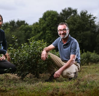 two men sitting on a field with trees in the background