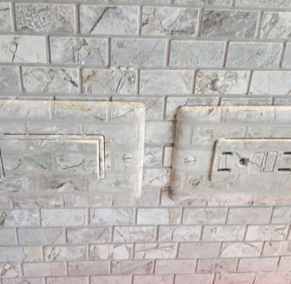 Switch plate faux finished to match the marbled tiles of this backsplash to hide them nicely.