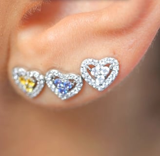 a close up of a pair of ear piercings with a heart shaped diamond