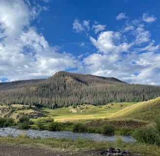 a mountain scene with a river and a mountain in the background