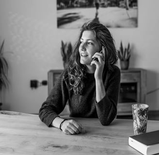 Femme souriante au téléphone représentant un échange humain et bienveillant