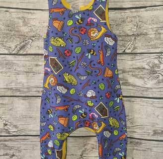 a baby's overalls with a blue and yellow romper with garden creatures forest school print