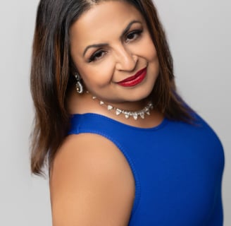 A woman wearing a blue dress with a soft smile.