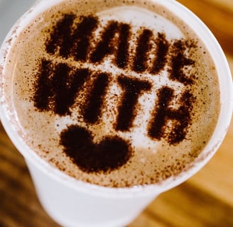Latte art heart with “made with love” message on a coffee cup