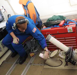 NOAA operator releases a dropsonde aboard a WP-3D Orion reconnaissance Hurricane Hunter aircraft from the inside.