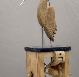 A carved wooden bird whose head and beak are a hair clip. A mechanism to open the beak is visible.