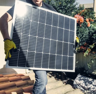 A man displaying the front surface of a solar panel during the installation process