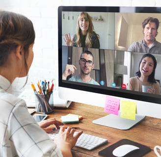 a woman sitting at a computer screen with a video chat